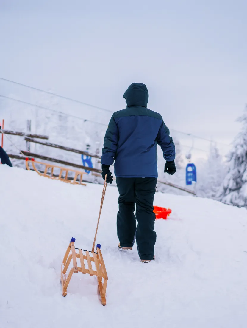Rodelspaß im Harz – verschneiter Wintertag mit Schlitten und dicker Winterkleidung
