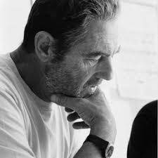 Image en noir et blanc d'un homme de profil portant un t-shirt. Il pose son menton sur sa main et a l'air absorbé.