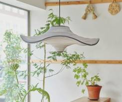 Flying pendel med bølgende skærm i blød hvid hænger over grønne planter i et lyst rum. Det lette og luftige design tilfører naturlig elegance og japansk-inspireret ro.