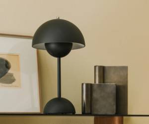 Schwarze Tischleuchte mit Kuppelschirm und Kugelfuß neben metallischen Vasen auf einem Sideboard