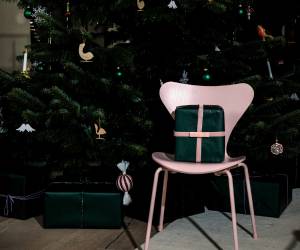 Pink chair with wrapped gift in front of a decorated Christmas tree.
