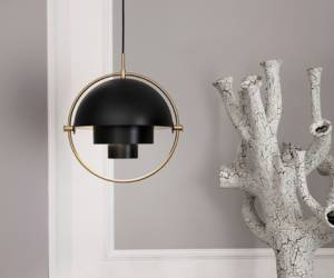 Schwarz-goldene Multi-Lite Pendelleuchte von GUBI vor grauer Wand