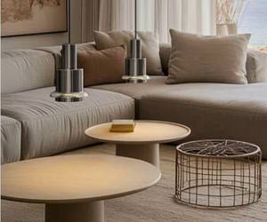 Dunkle Pendelleuchten über beigem Ecksofa mit runden Holz-Couchtischen