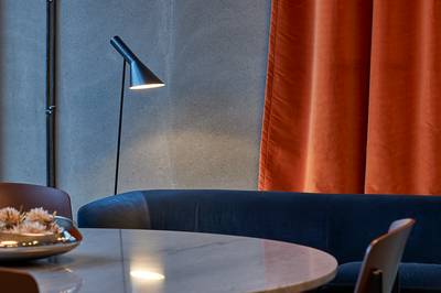 Questa immagine mostra l'iconica lampada da terra AJ di Louis Poulsen, caratterizzata da un paralume a forma di cono.