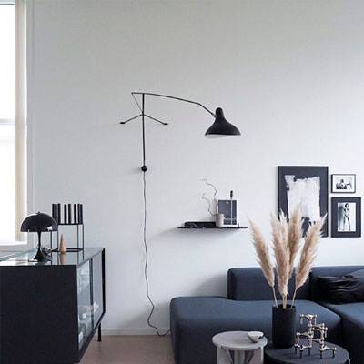 Esta imagem mostra um candeeiro de parede Mantis preto pendurado num ambiente de sala de estar