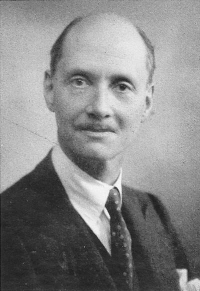 Vintage fekete-fehér portré egy rövid hajú, bajuszos, öltönyös, nyakkendős férfiról. Semleges háttér előtt ül.