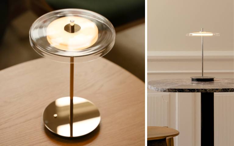 Candeeiro de mesa elegante com abajur de vidro transparente e base metálica fina colocada numa mesa com luz quente e atmosférica.