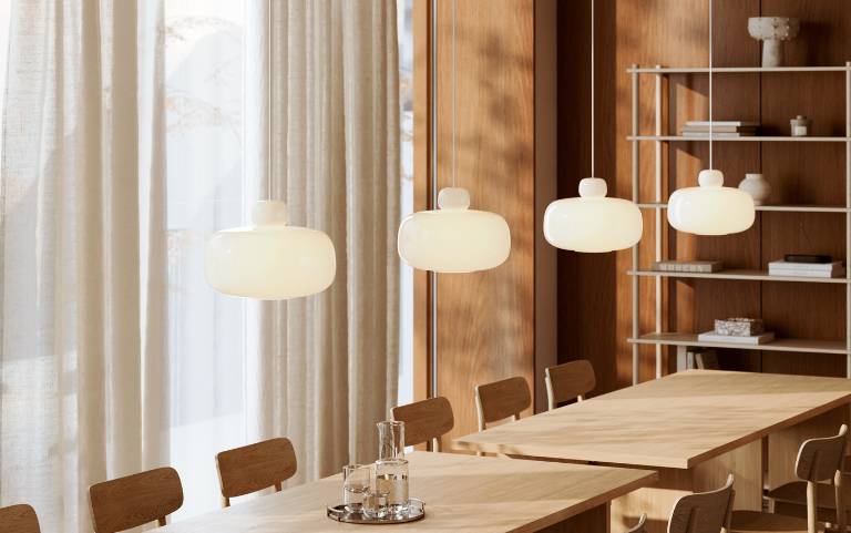 Modern Woud Stone pendant lights suspended above light-colored wooden furnishings with a Scandinavian touch.