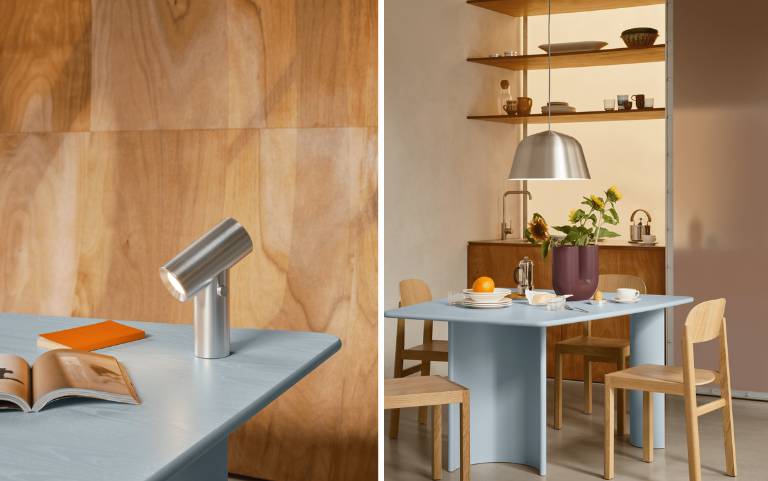 Mesa e candeeiro suspenso minimalistas em metal escovado, colocados de forma acolhedora numa sala de jantar escandinava luminosa com madeira e cores suaves.