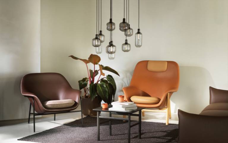 Modern Normann Copenhagen Amp függőlámpák egy stílusos társalgó sarok felett, meleg dizájner bútorokkal.