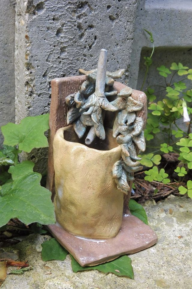 Photo of a ceramic water butt near plants
