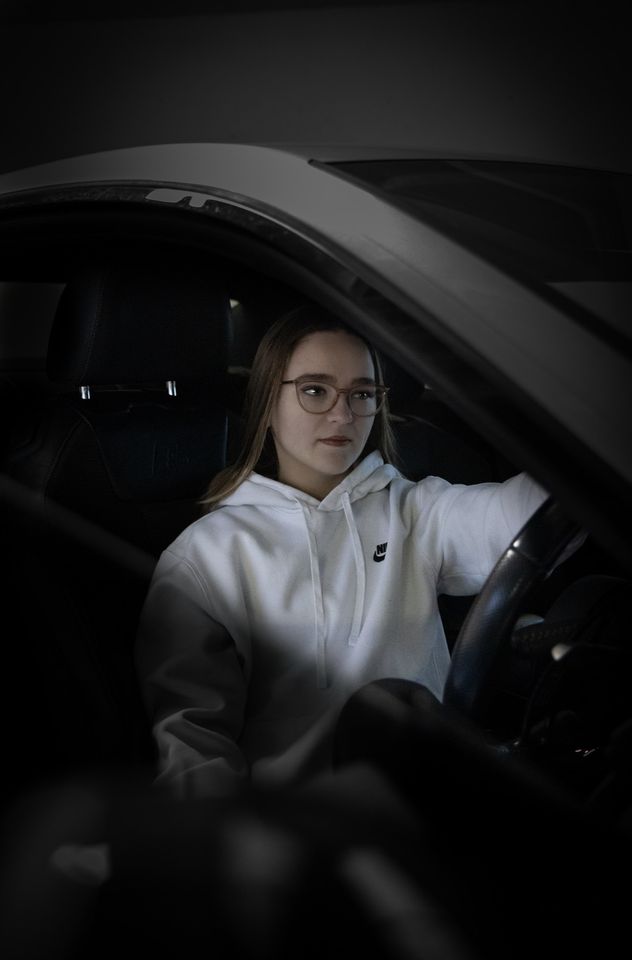 Photo of woman in white hoodie in car driver's seat