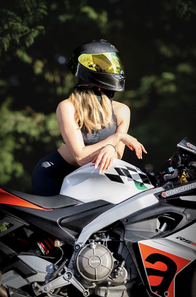 Photo of woman wearing motorbike helmet leaning on bike
