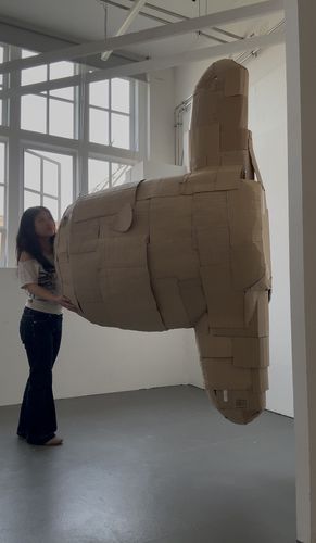 A woman standing next to a cardboard sculpture