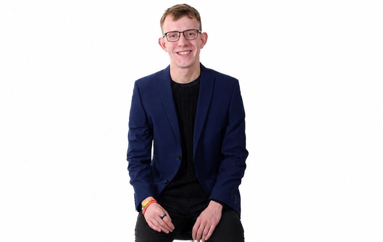 Jack Palmer smiling at camera, wearing blue blazer and black t-shirt