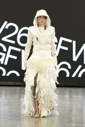 Female model wearing white dress with tassled skirt and hood on GFW2026 catwalk