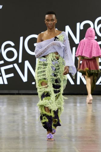 Female model wearing purple top with green and purple trousers with gaping holes on GFW2026 catwalk