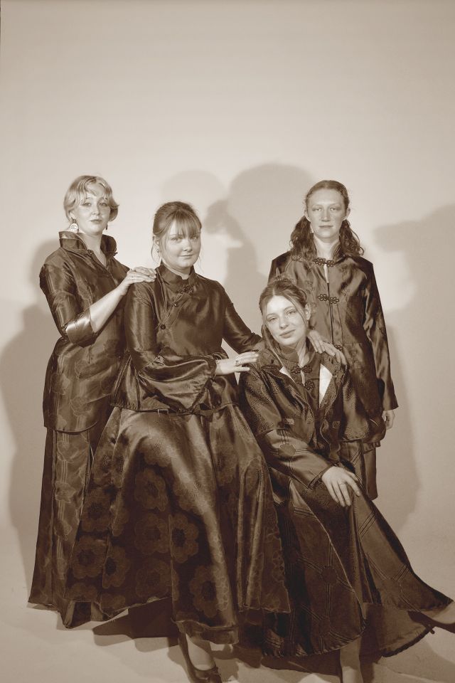 Sepia photo of four female models in long silky dresses