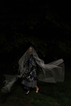 Photo of model wearing silver blue coat, grey skirt and grey veil