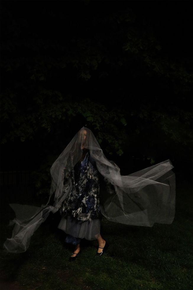 Photo of model wearing silver blue coat, grey skirt and grey veil