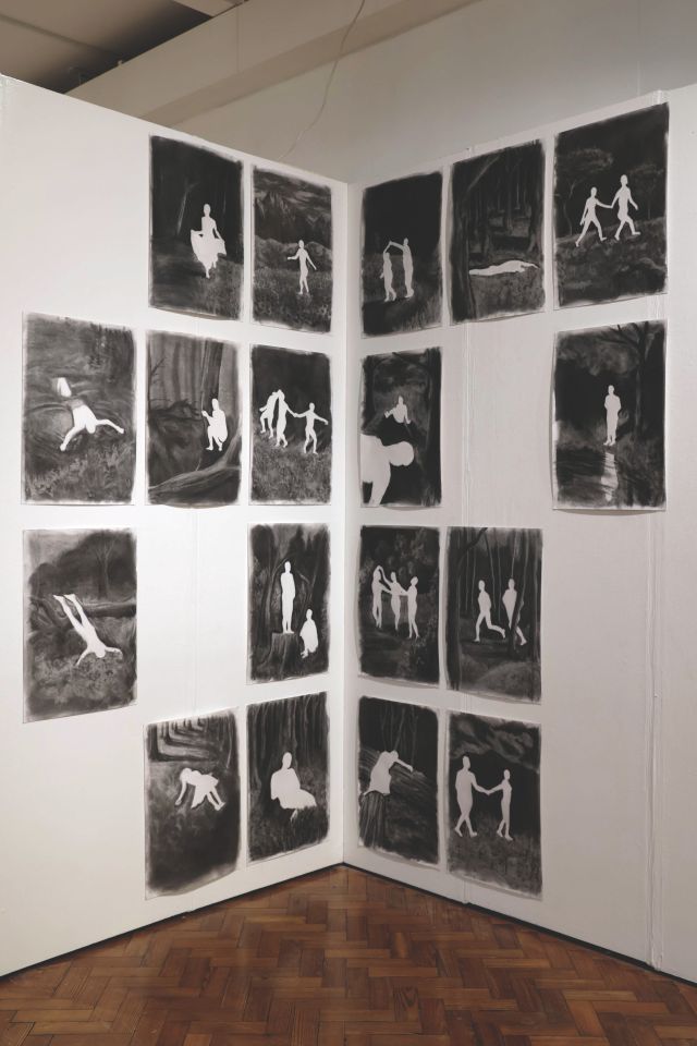 Many negative charcoal images of people in different poses on gallery wall