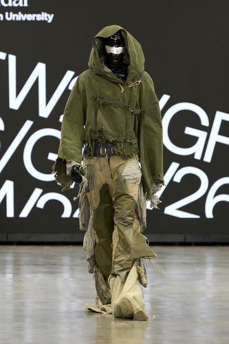 Model wearing black and silver facemask, green jacket and camo-style trousers on GFW2026 catwalk