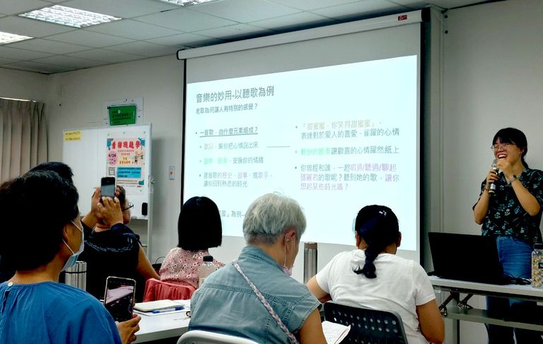 Amanda lee presenting a slideshow to a group in a classroom. Attendees are seated, some taking notes or photos. Text on the screen is in Chinese.