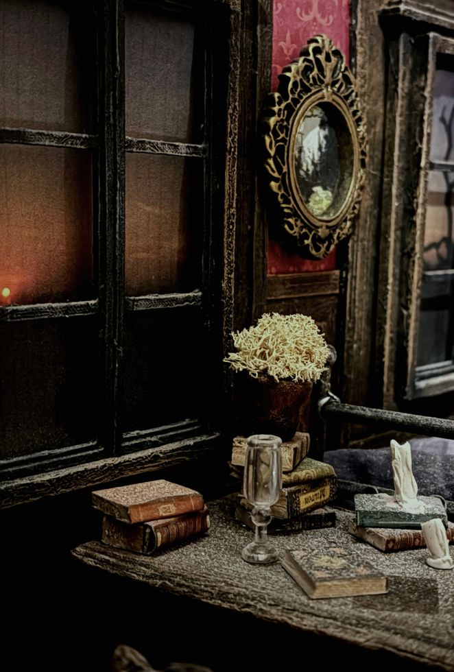 Illustration of an old fashioned room with an ornate mirror and a desk covered in books, and an empty glass