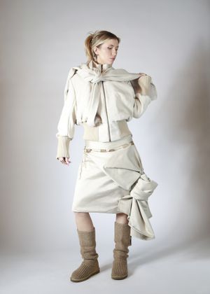 Female model wearing beige skirt and top with brown boots