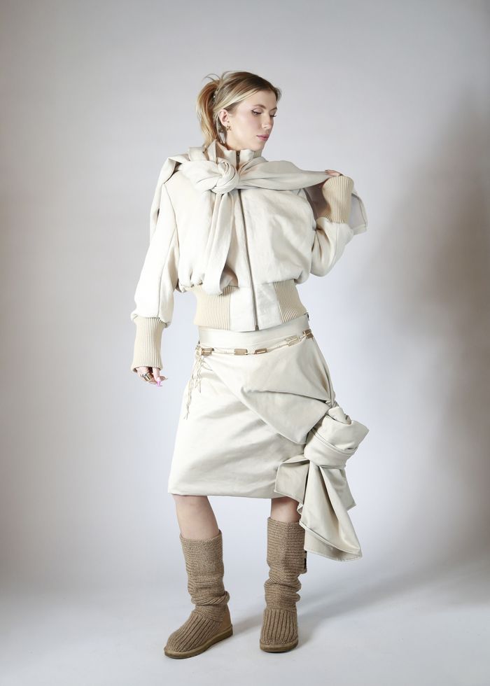 Female model wearing beige skirt and top with brown boots