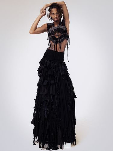 Male model wearing black skirt and threaded leather short top
