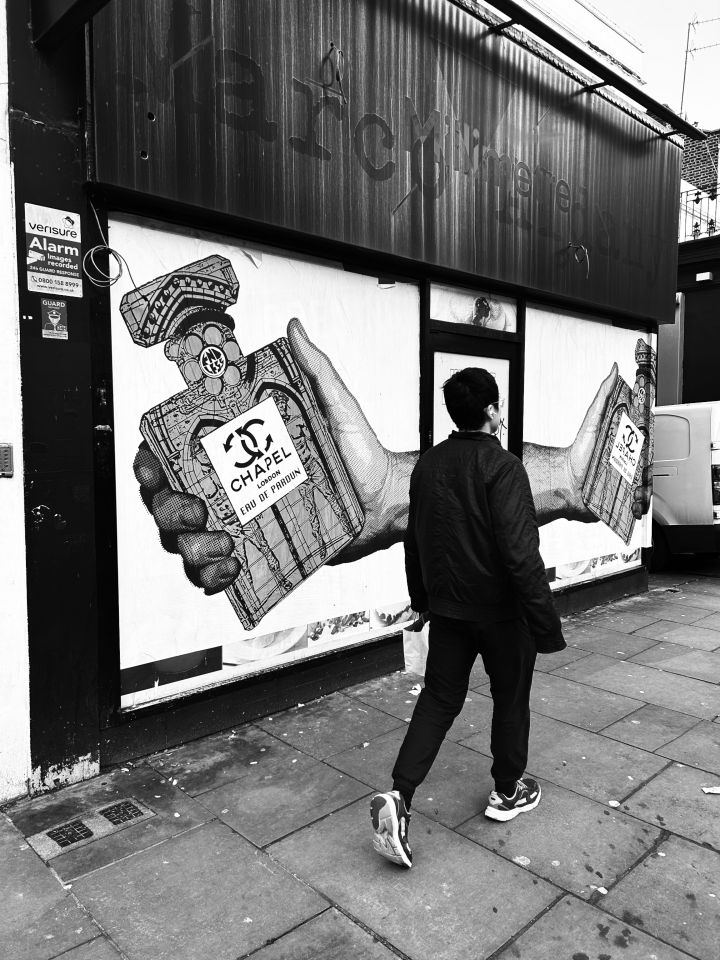 Black and white photo of posters featuring Endless's Chapel perfume bottle on an empty shop front