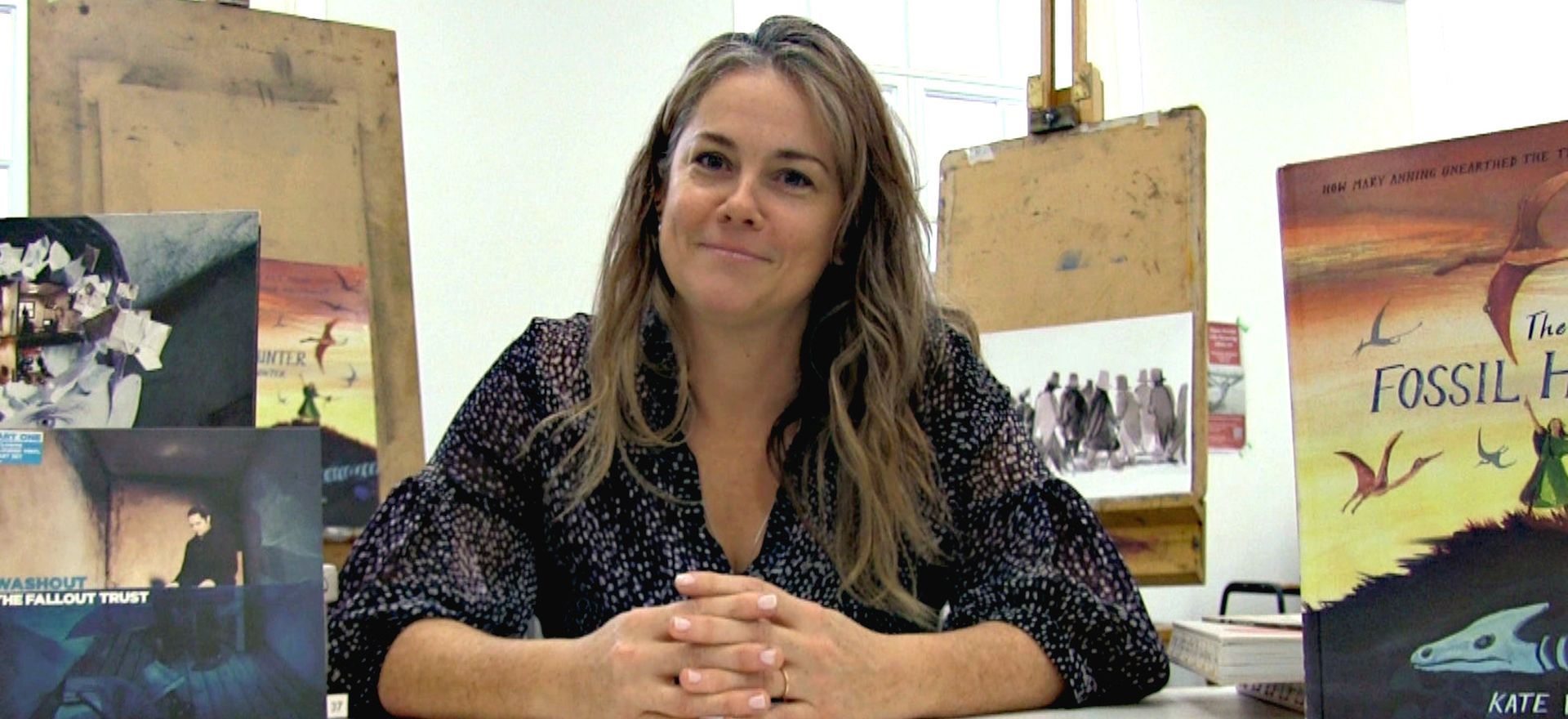 Kate winter sitting at desk surrounded by her illustration work