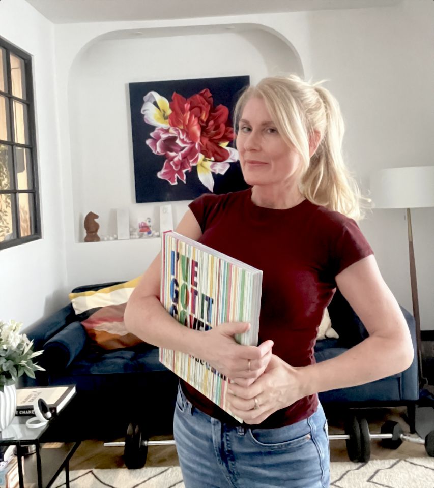 Lisa Sheehan standing in lounge holding book titled "I've Got it Covered"