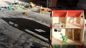 Film still showing a doll's house and various toy dinosaurs and animals