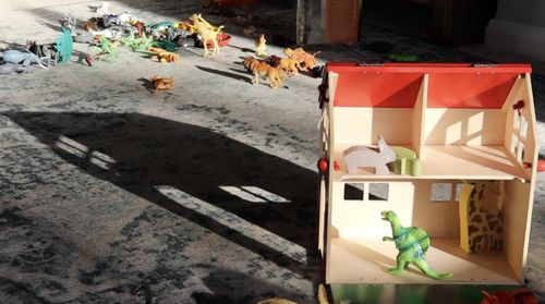 Film still showing a doll's house and various toy dinosaurs and animals
