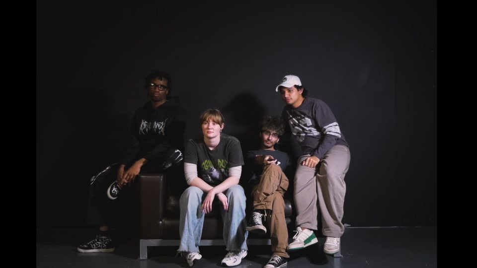 Film still of four people sitting on sofa