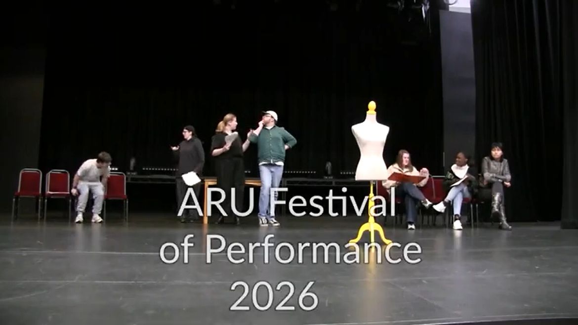 Performers on stage with a mannequin at ARU Festival of Performance 2026, rehearsing with scripts in a theater setting.