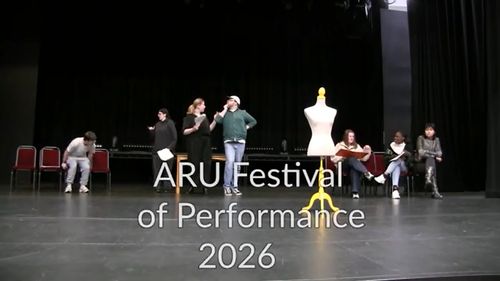 Performers on stage with a mannequin at ARU Festival of Performance 2026, rehearsing with scripts in a theater setting.