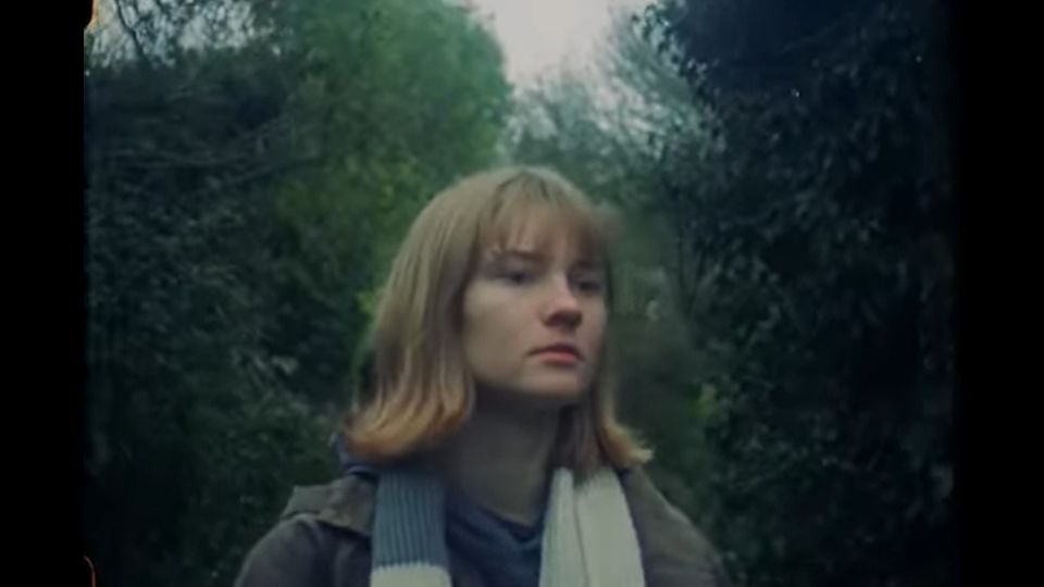 Film still of young woman in trees