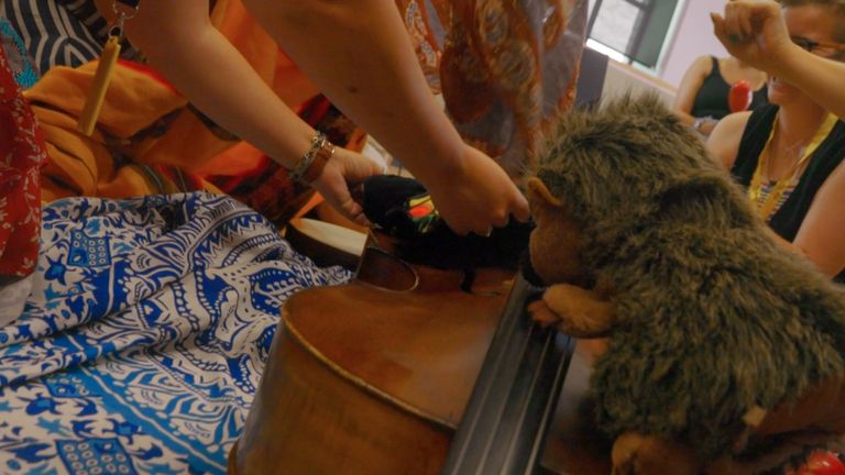 A collection of colourful fabrics, puppets and a cello