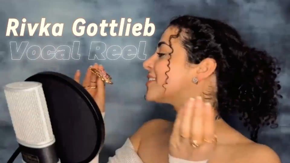 Rivka singing into a microphone, with curly hair and expressive gestures. Text overlay says "Vocal Reel" on a blue background.