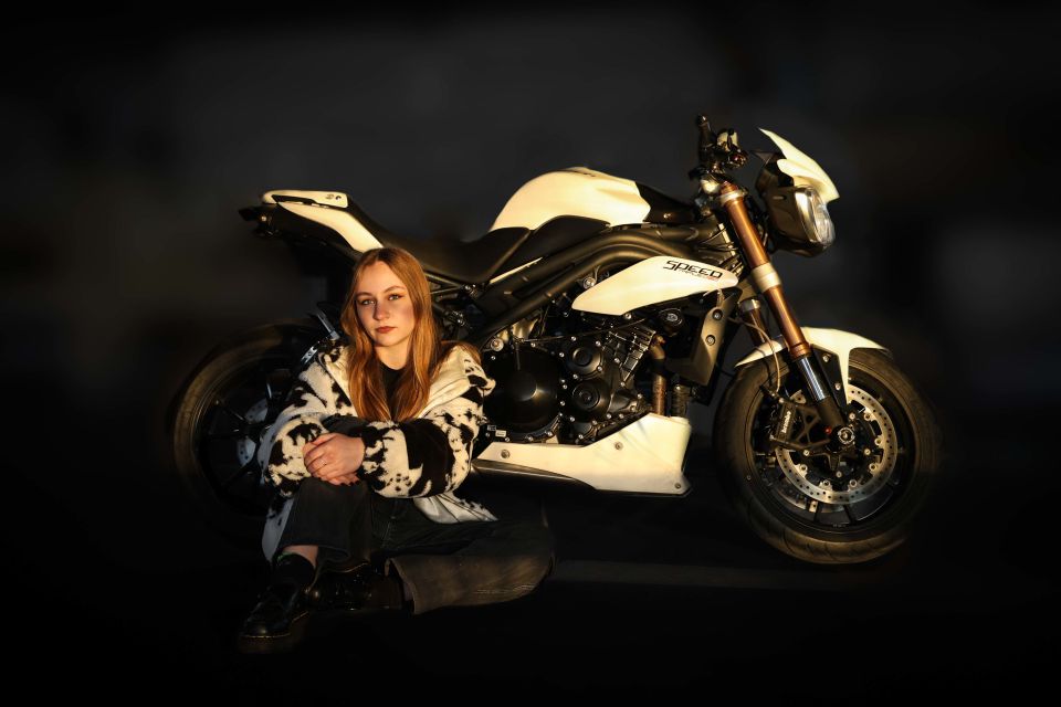 Photo of a woman sitting in front of white motorbike