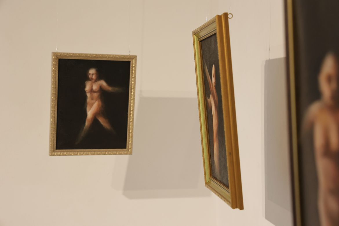 Three gold-framed paintings of naked woman on gallery wall