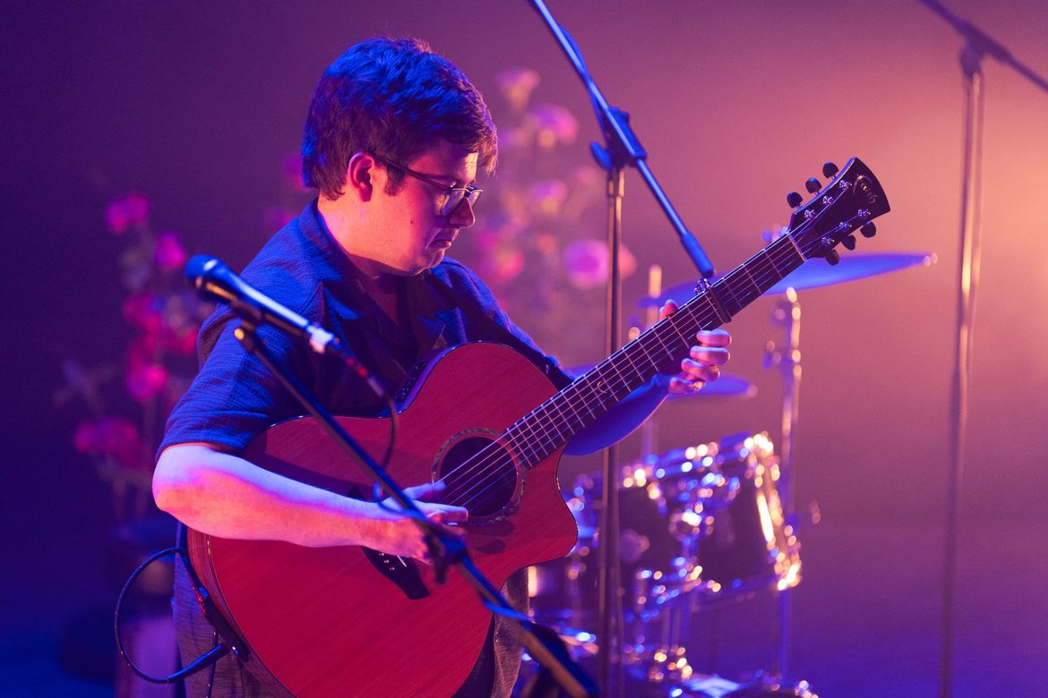 Dan Parry playing guitar on stage in front of drumkit
