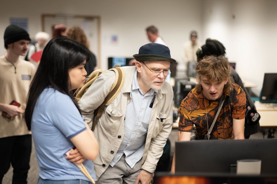 A young woman and man and an older man attentively look at a computer screen