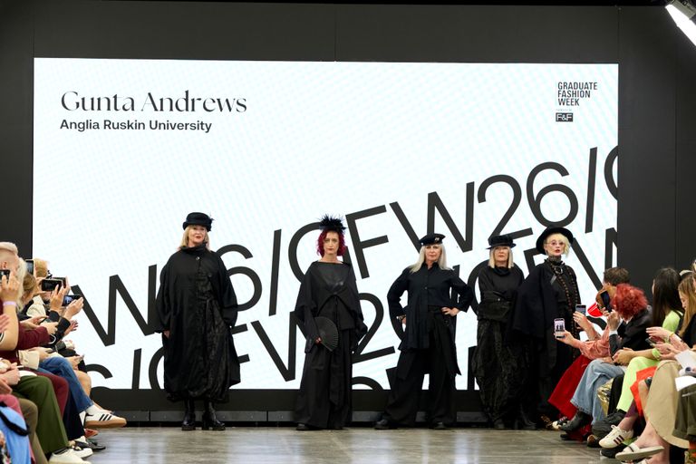 Five female models standing in a row on GFW2026 catwalk wearing black outfits