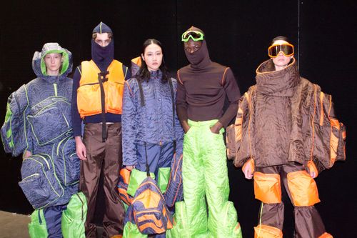 Five models in futuristic, colorful outfits with puffy textures and vibrant accessories, set against a dark background.