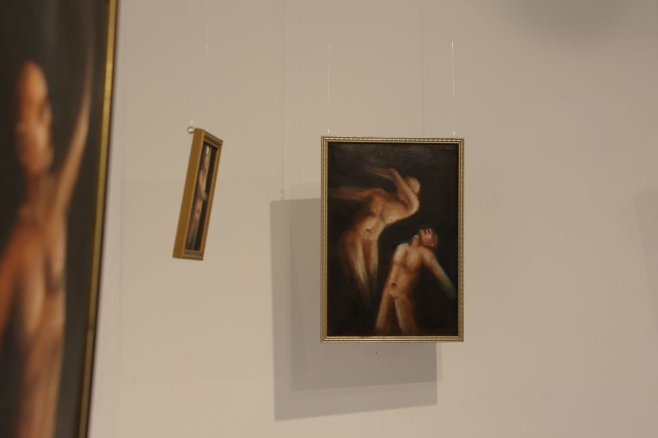 Three gold-framed paintings of naked people on gallery wall