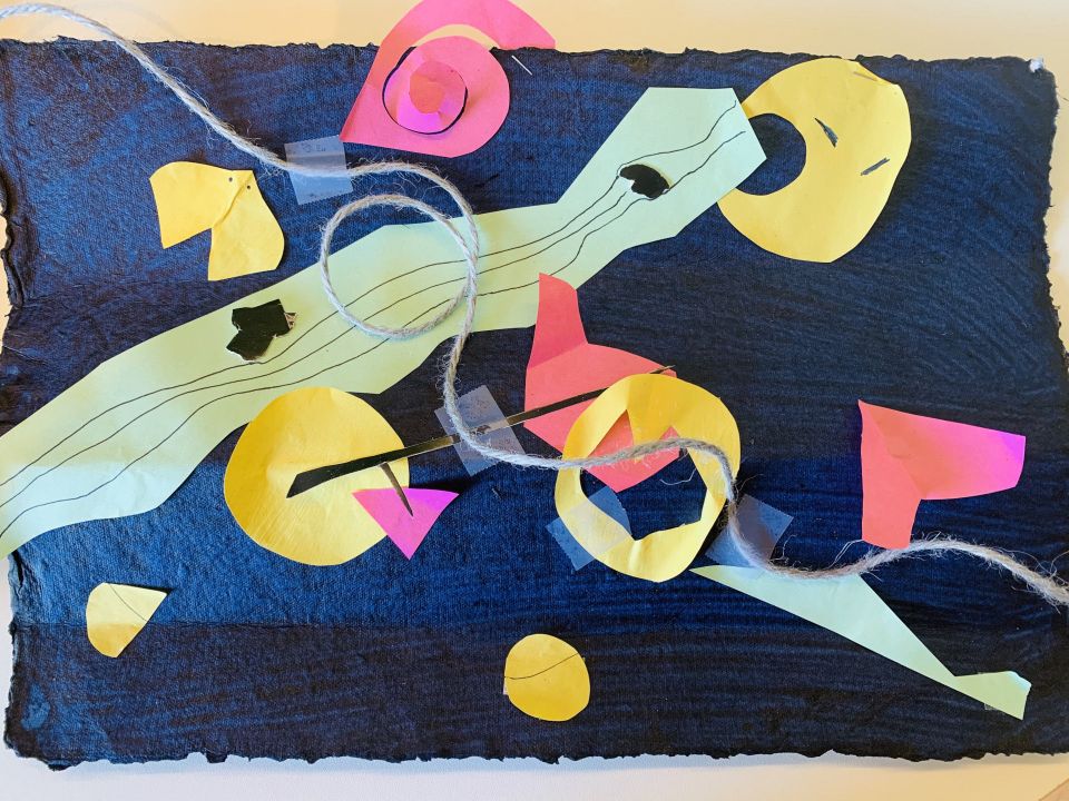 Abstract collage with yellow, pink, and green paper shapes on a dark background, accented by twine and drawn lines.